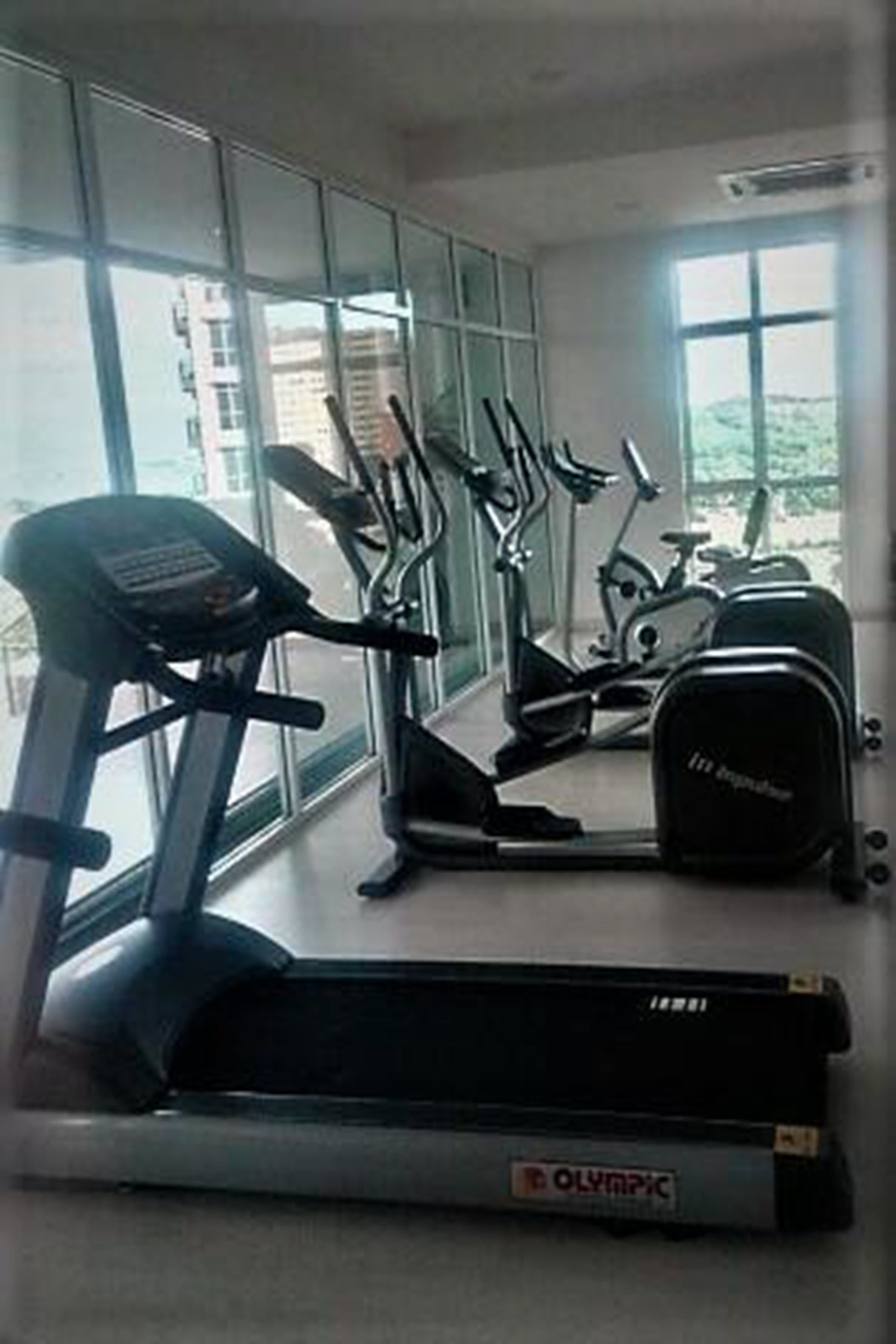 Uma academia com esteira ergométrica, elíptico e bicicletas fixas.