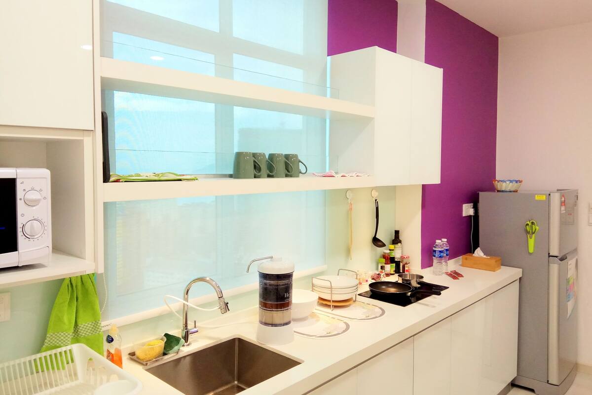 A modern kitchen with white cabinets, a stainless steel sink, and a refrigerator.