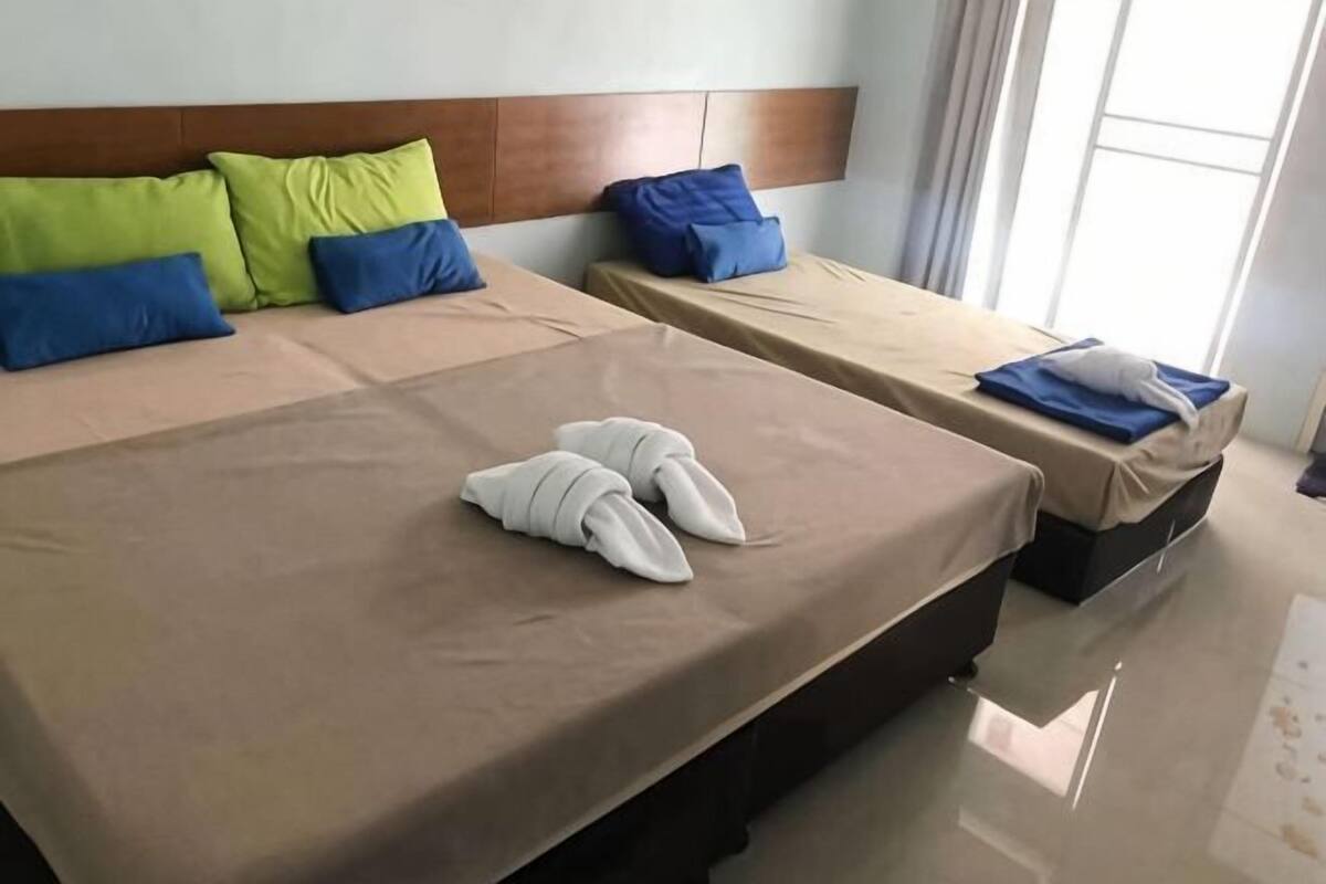 Ein Hotelzimmer mit zwei Betten, jeweils mit Kopfteil, Kissen und Handtüchern.