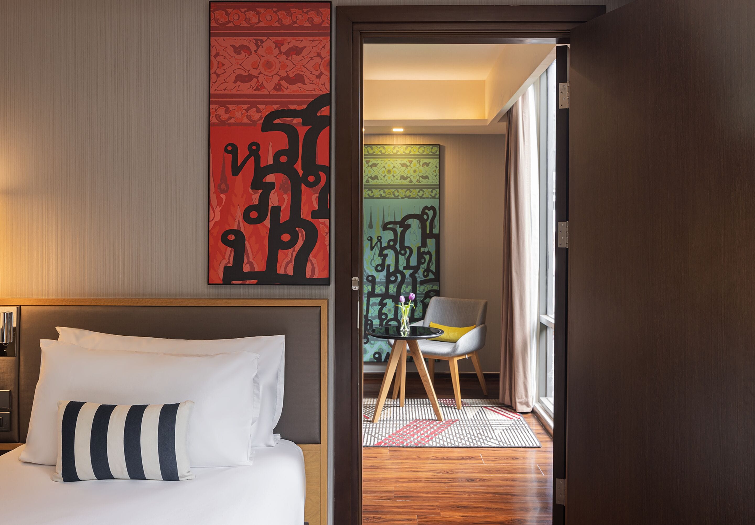 Una habitación de hotel con una cama, una silla, una mesita y un adorno en la pared.