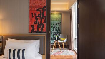 Una habitación de hotel con una cama, una silla, una mesita y un adorno en la pared.
