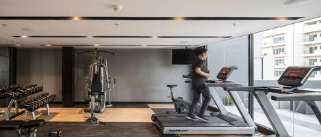 Un gimnasio moderno con cintas de correr, mancuernas y máquinas de pesas.