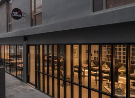 Ένα σύγχρονο κτίριο με μια πινακίδα που γράφει «The Lodge». Στο εσωτερικό, υπάρχουν πολλά τραπέζια και καρέκλες διατεταγμένα σε μια τραπεζαρία.