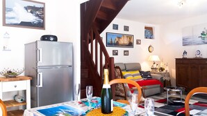 Un ambiente compatto con angolo cottura, zona pranzo con tavolo imbandito per due persone, divano e una scala.