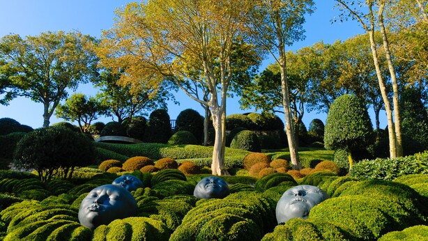 Un giardino curato con sculture sferiche e siepi ben potate.