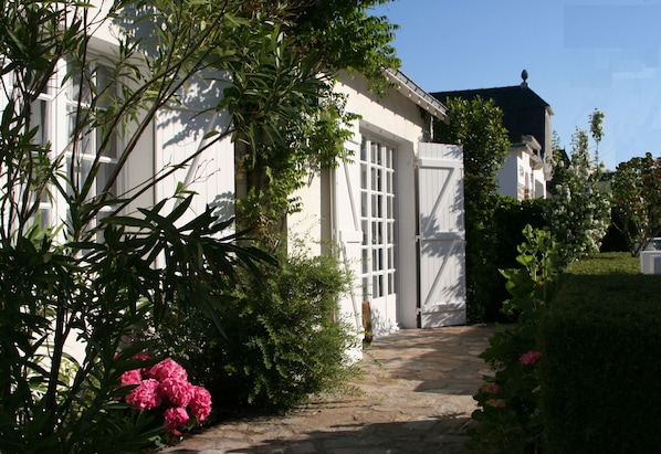 Un bâtiment blanc doté de grandes fenêtres et d’un chemin de pierre menant à une entrée fermée par un portail.