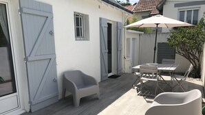 Un patio con una mesa, sillas y una silla de plástico, además de una puerta con un ventanal.