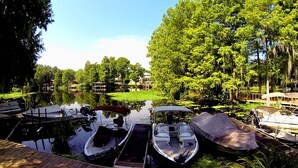 Um cais tranquilo à beira do lago com vários barcos, cercado por vegetação exuberante e árvores.