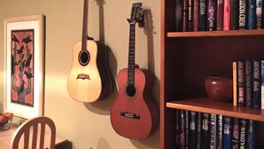 Two guitars hanging on a wall and a bookshelf filled with books. - Affordable Month to Month In The Heart Of Chicago. 30 Day Minimum Bookings. (Chicago)