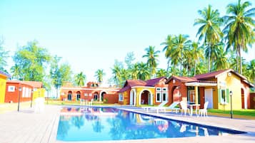Una piscina al aire libre, sombrillas, sillones reclinables de piscina