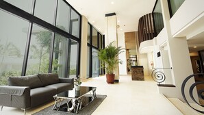 A modern hotel lobby with a sofa, coffee table, potted plant, and a spiral staircase. - Green Point Residence Hotel (Bangkok)
