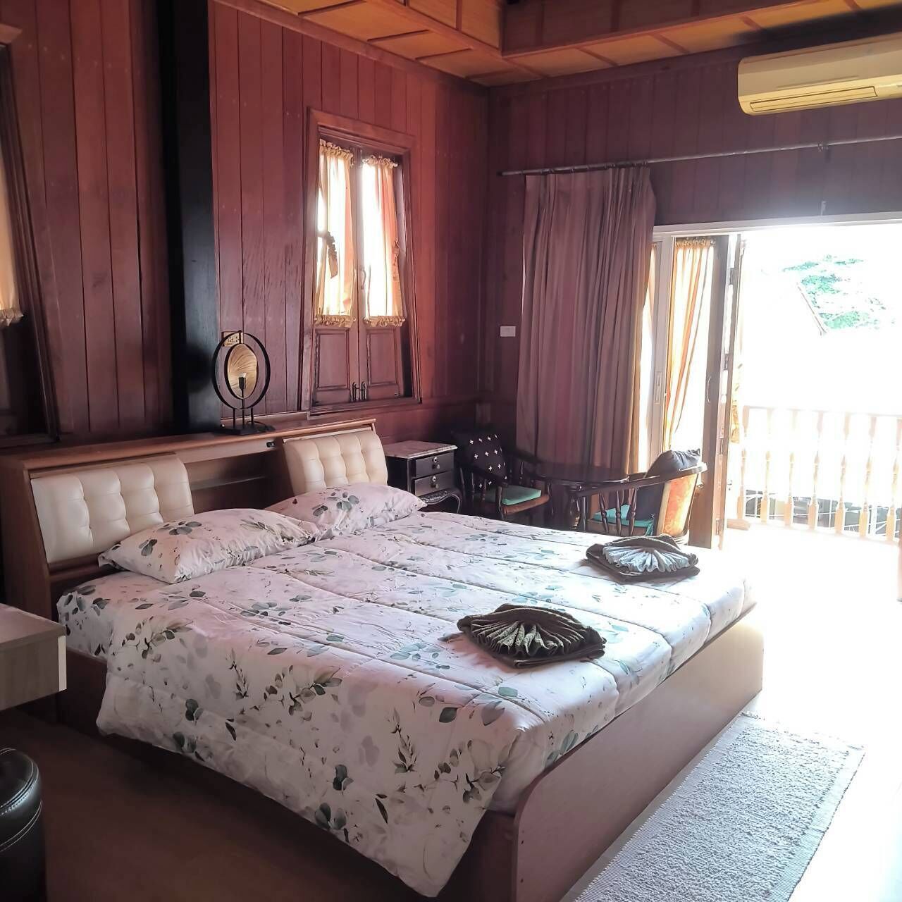 Een slaapkamer met een groot bed, houten wanden, een klein bureau en een stoel.