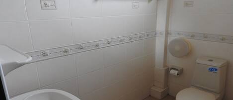 A bathroom with a white sink, toilet, and a small trash bin.
