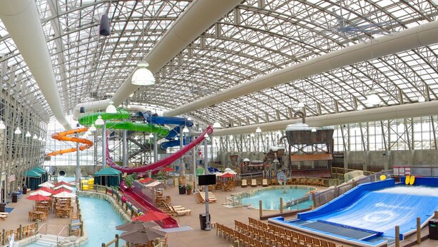 Parque acuático interior con múltiples toboganes, piscina y zonas de descanso.