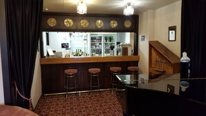 Zona de bar con mostrador, taburetes y pared espejada.
