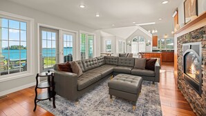 A spacious living room with a large sectional sofa, a fireplace, and a view of the outdoors. - Waterfront Beach House - 2700 Sq Ft, Fiber, mooring (Friday Harbor)