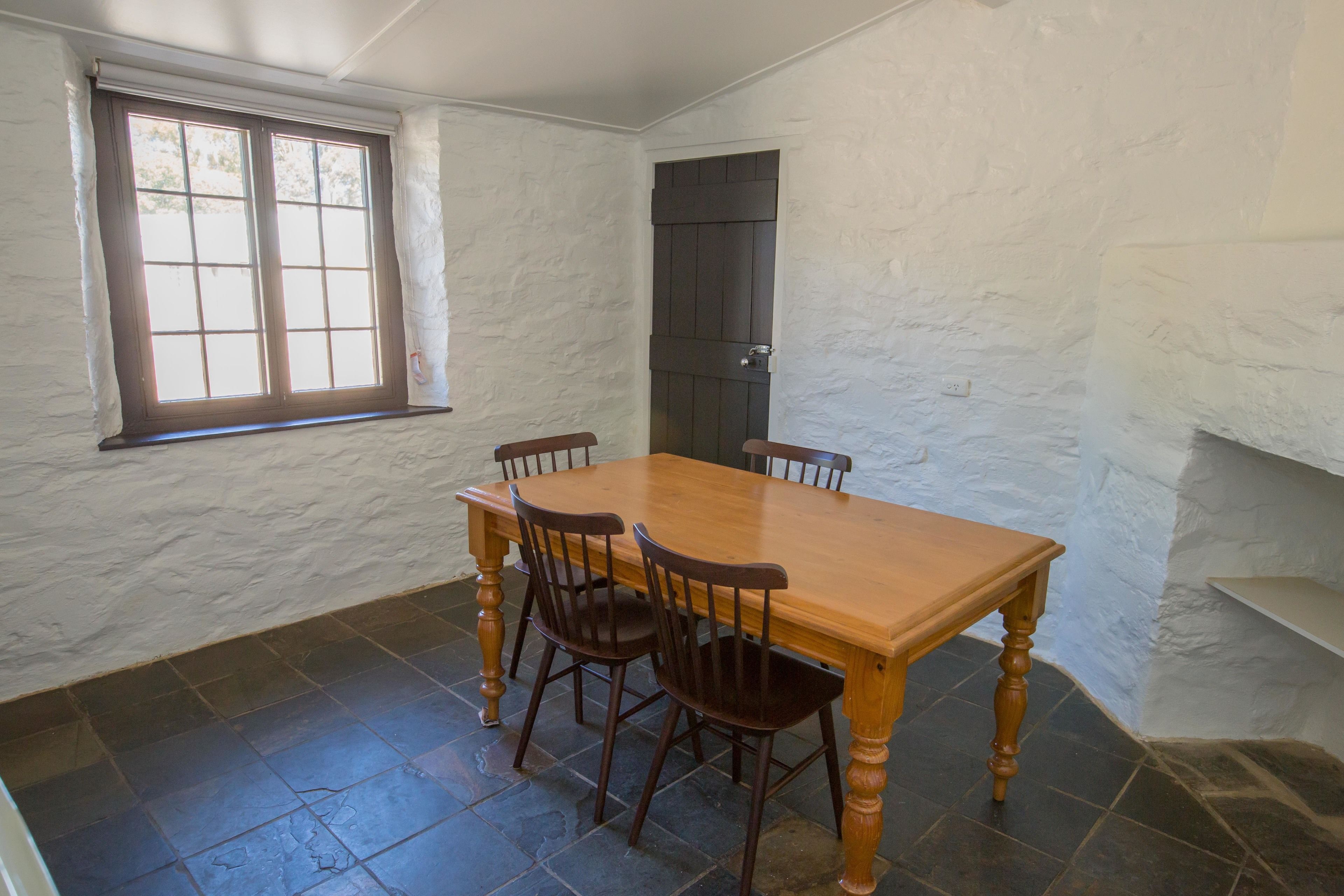 Comedor con una mesa y sillas de madera, una ventana y una puerta.