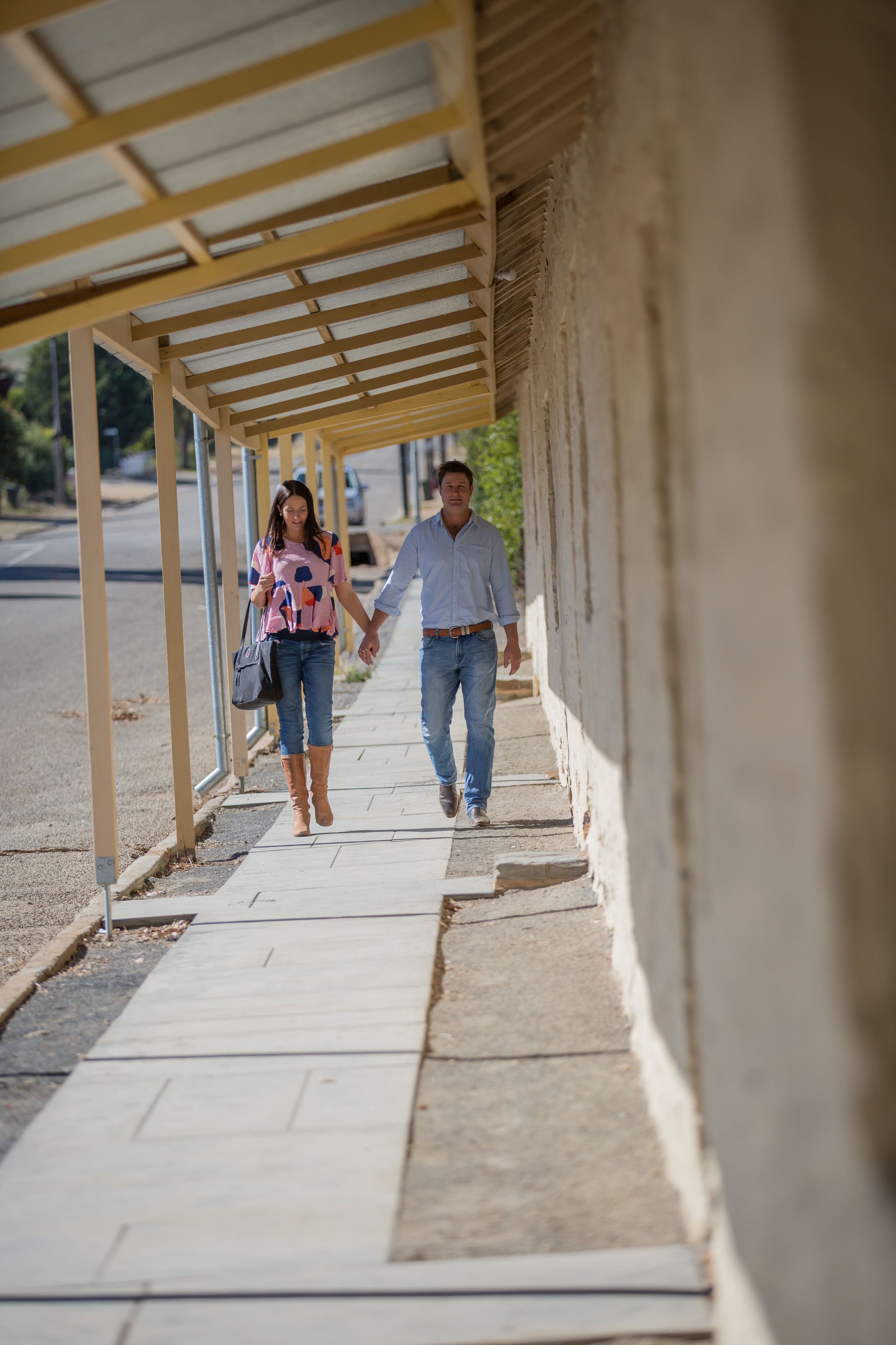 A covered walkway with a simple, functional design, featuring a concrete floor and a metal roof structure.