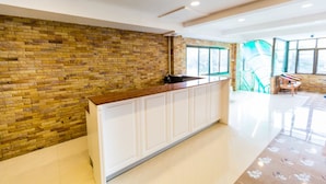 A reception area with a stone wall, a wooden counter, and a view of a staircase and outdoor area. - Marina Jomtien Beach (Pattaya)