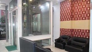 A reception area with a glass door, a reception desk, two black leather sofas, and a patterned wall. - T Hotel Jalan Tar (Kuala Lumpur)