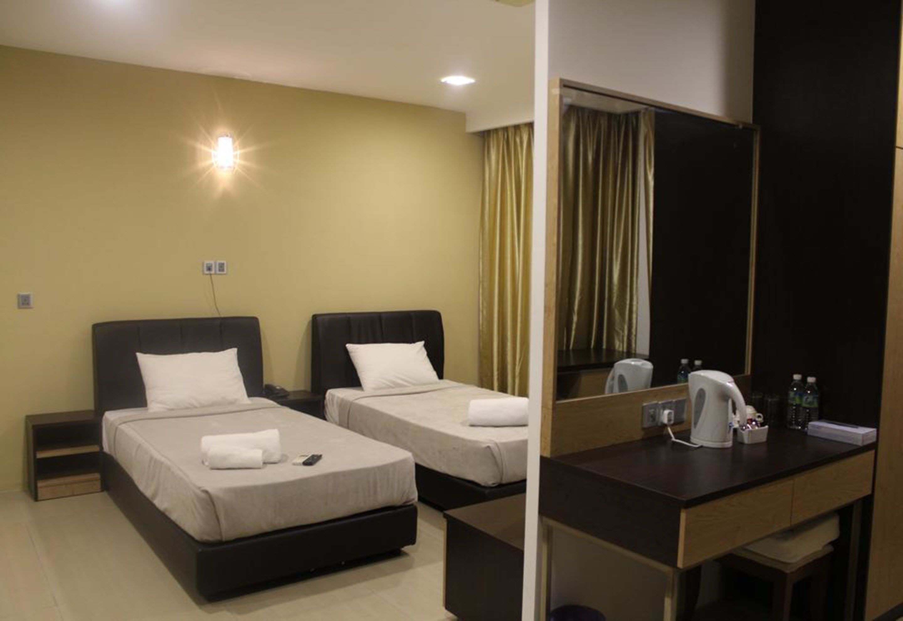 A hotel room with two beds, a desk, a mirror, and a nightstand.