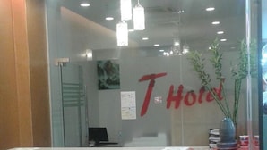 A hotel reception desk with a red and white color scheme, a glass partition, and a sign that reads "Hotel". - T Hotel Jalan Tar (Kuala Lumpur)
