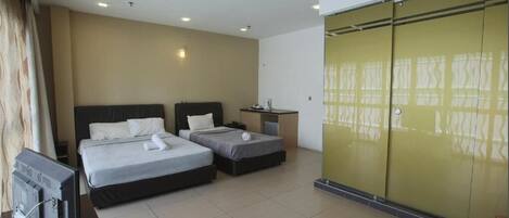A hotel room with two beds, a television, a wardrobe, and a small table.