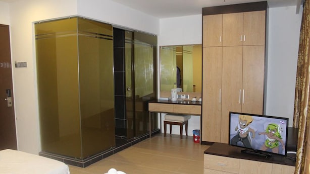 A hotel room with a bed, a TV, a wardrobe, and a bathroom with a glass shower enclosure. - T Hotel Jalan Tar (Kuala Lumpur)