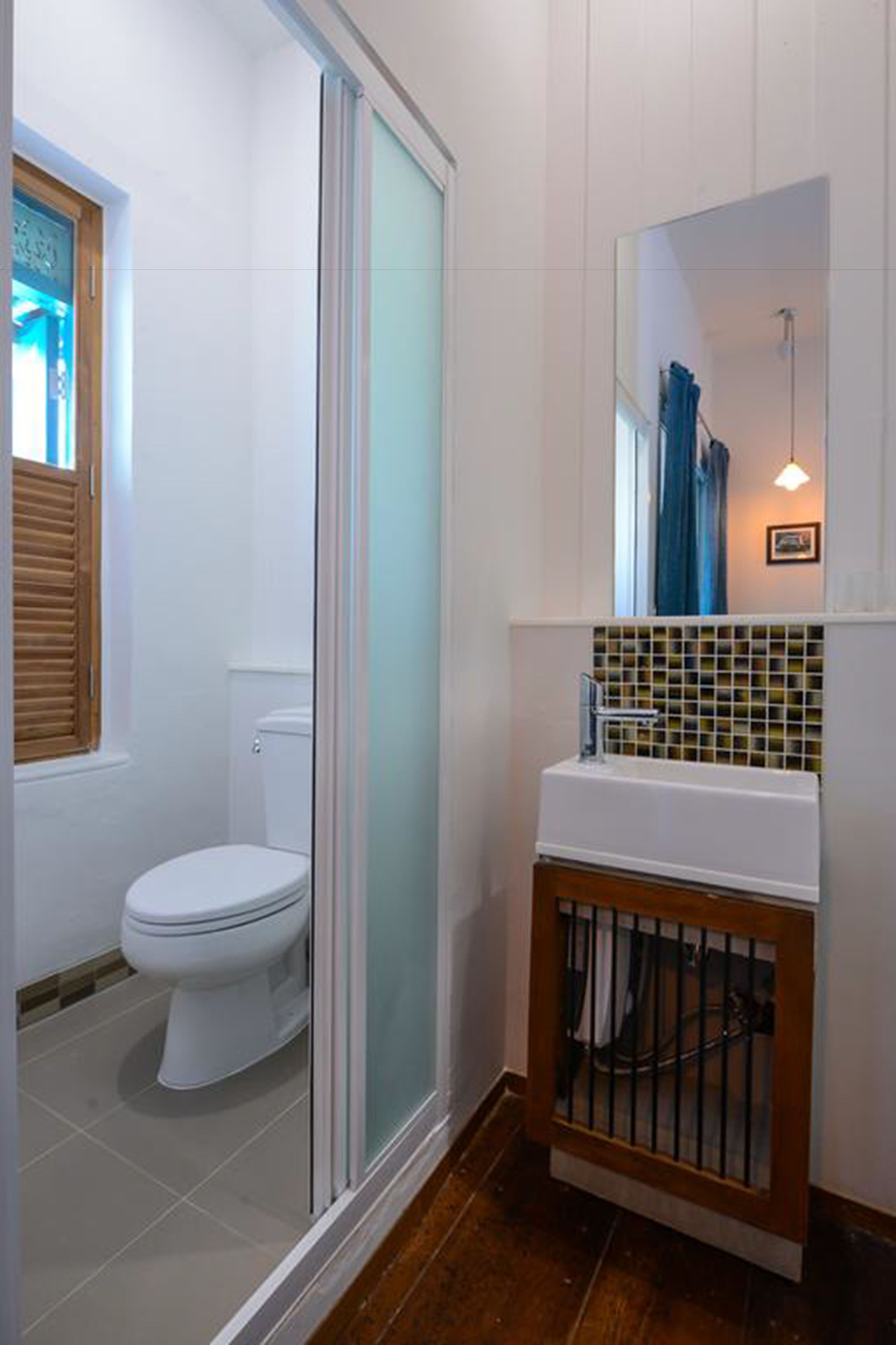 A bathroom with a toilet, a glass-enclosed shower, and a sink with a tiled backsplash.