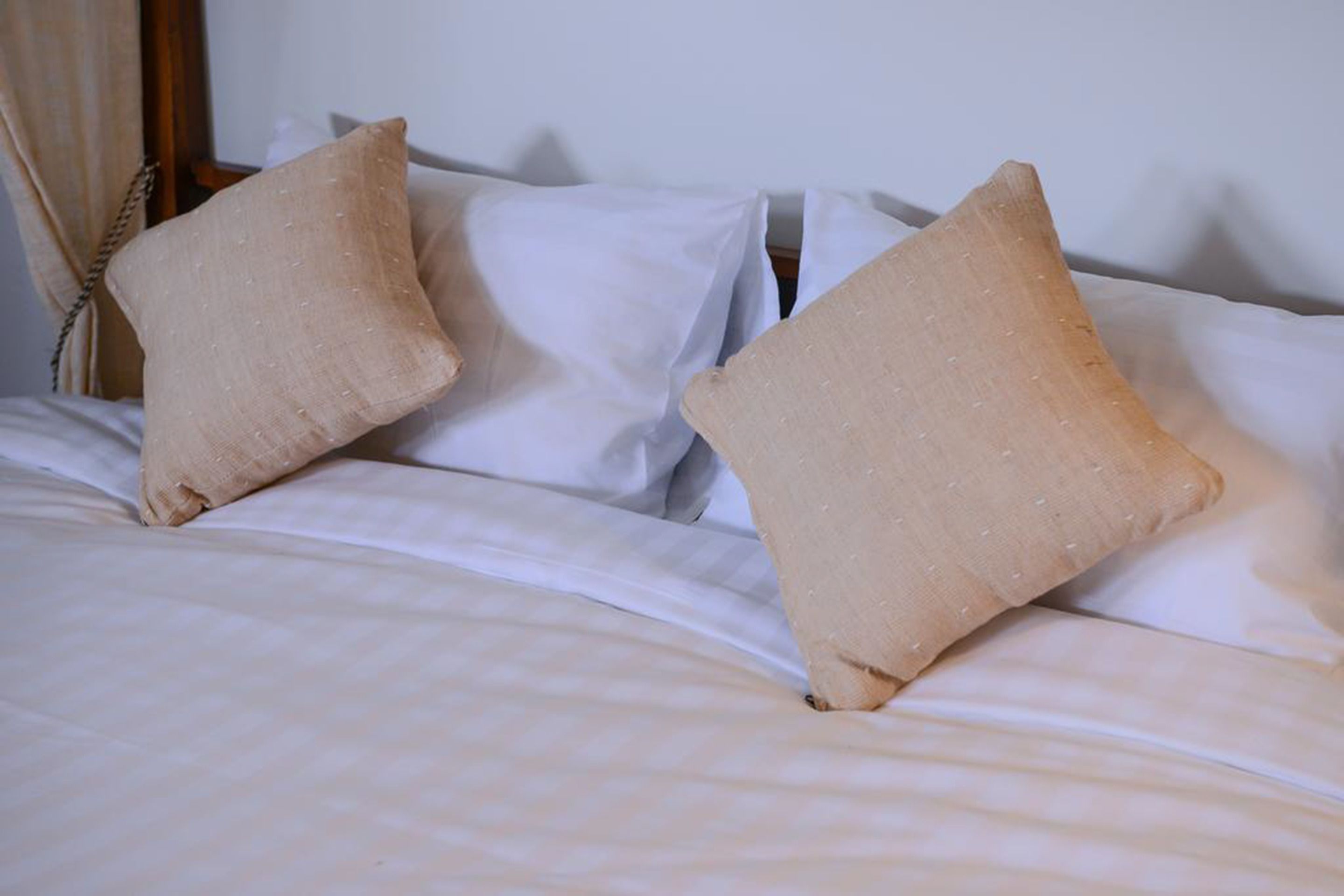 Ein Bett mit zwei beigen Kissen und einer weißen Bettdecke.