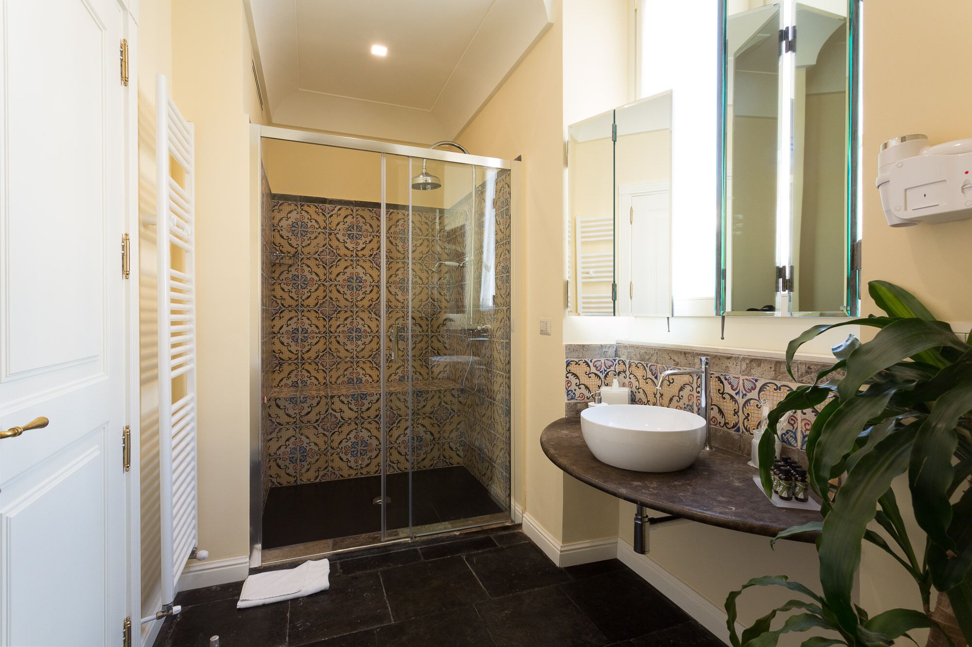 A bathroom with a glass shower enclosure, a white sink, and a mirror above it.