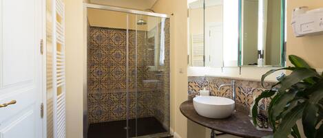 A bathroom with a glass shower enclosure, a white sink, and a mirror above it.