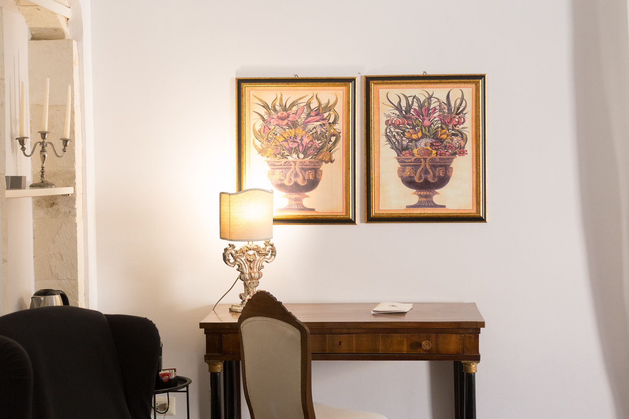 Une pièce comprenant un bureau, une chaise et deux tableaux représentant des motifs floraux, accrochés au mur.