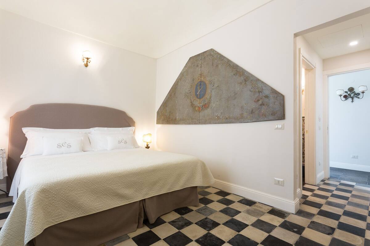 Une chambre à coucher avec un lit, un tableau accroché au mur et un sol à carreaux.