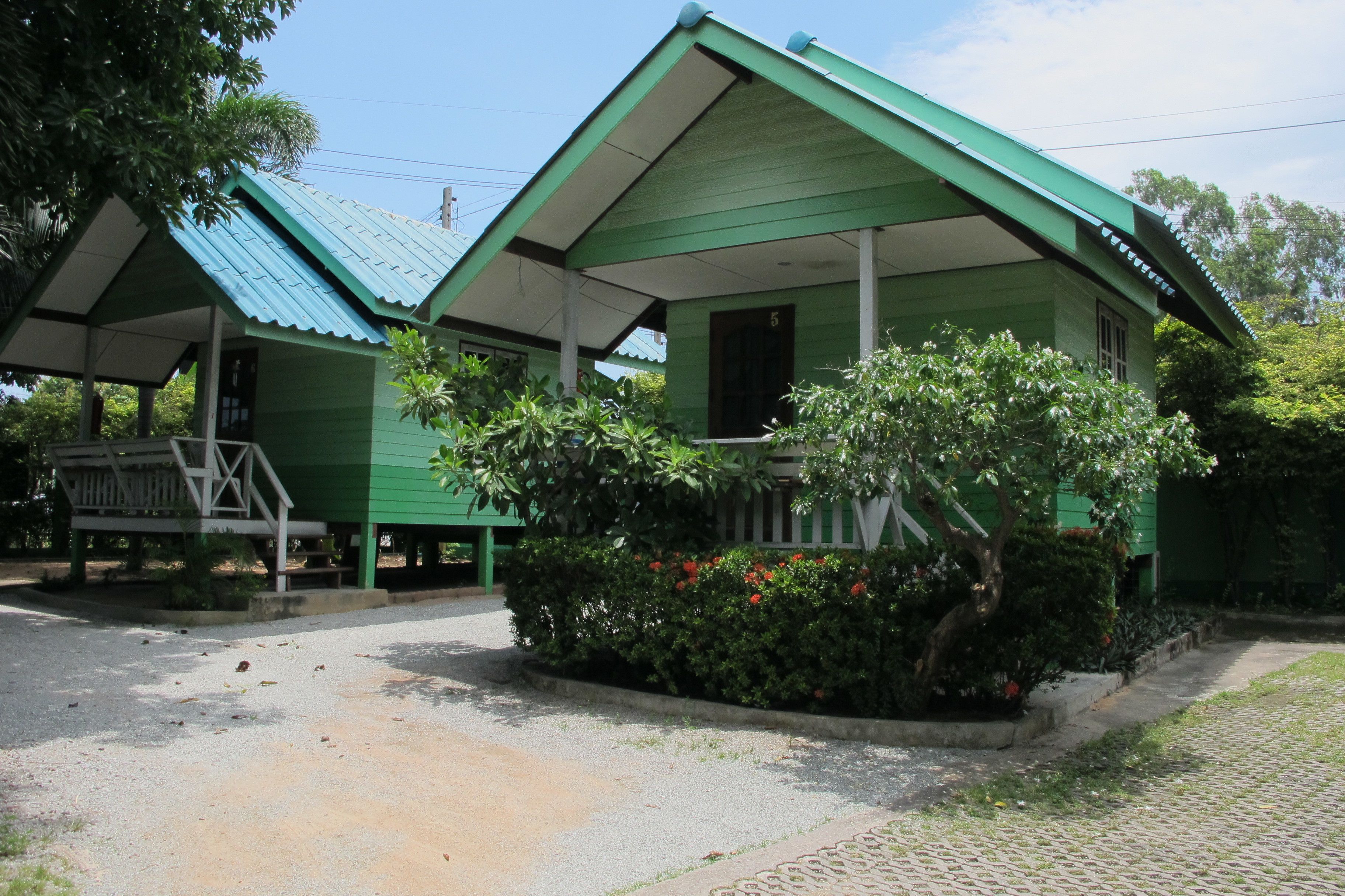 A row of green-roofed cabins with a covered porch and a small garden area.