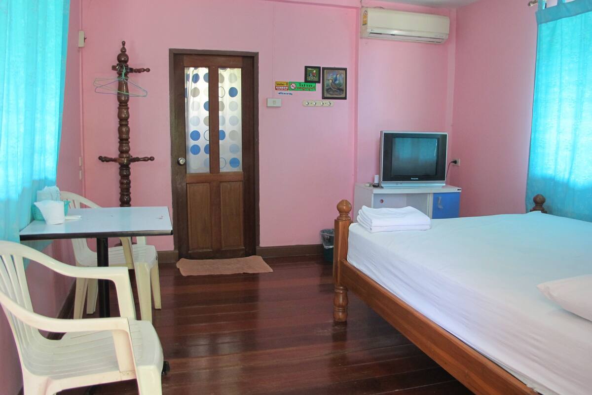 A room with a bed, a television, a desk, and a chair.