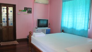 A bedroom with a bed, a television on a stand, a door, and a window with curtains. - The Green Resort Sri Racha (Si Racha)