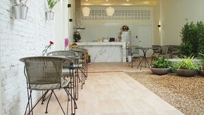A modern kitchen with a white countertop, a built-in oven, and a refrigerator. There are two pendant lights above the counter and a ceiling fan. - Shunli Hostel (Phuket)