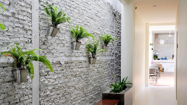 A hallway with a brick wall, potted plants, and a bench. - Shunli Hostel (Phuket)