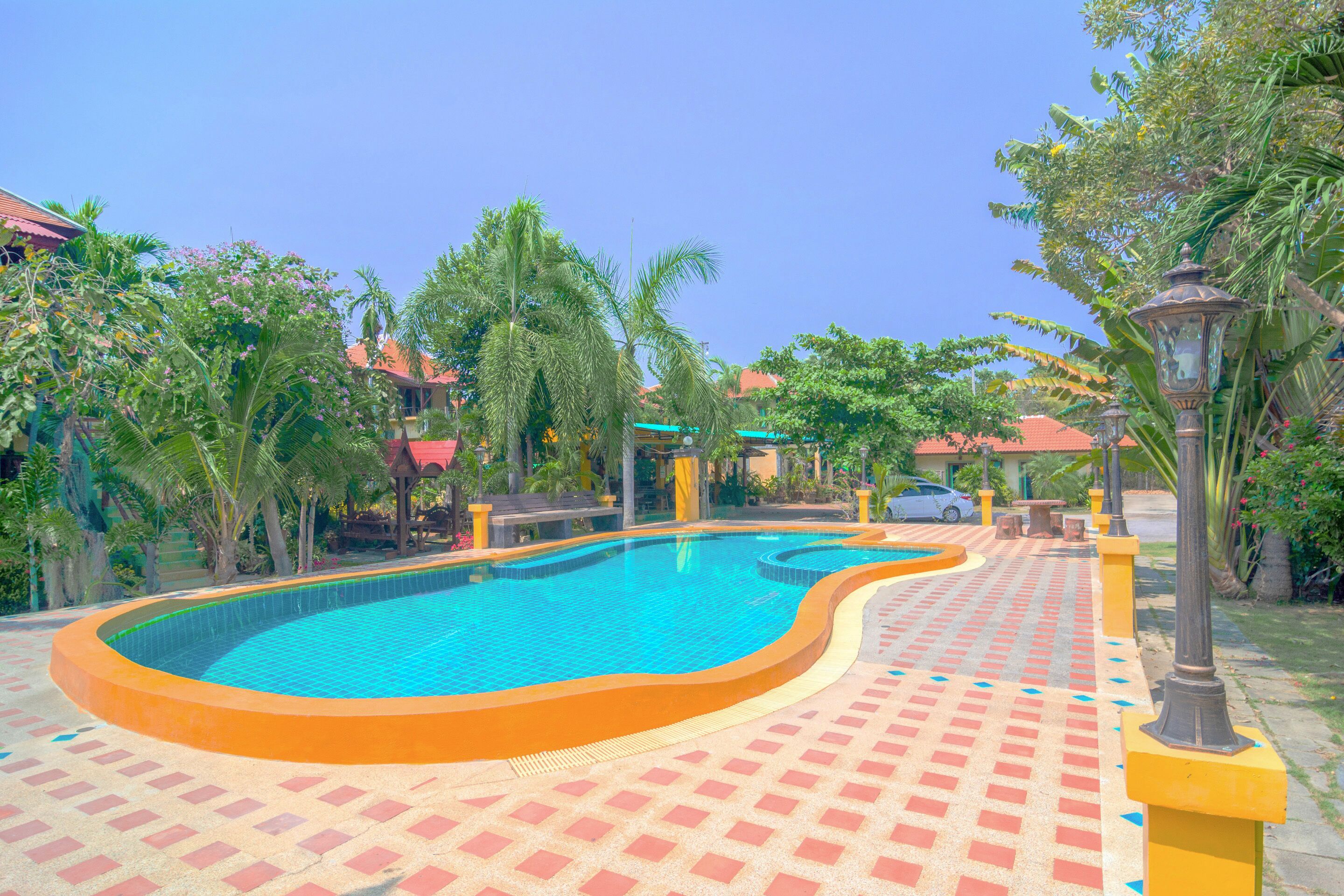 A swimming pool with a tiled deck, surrounded by palm trees and a clear blue sky.