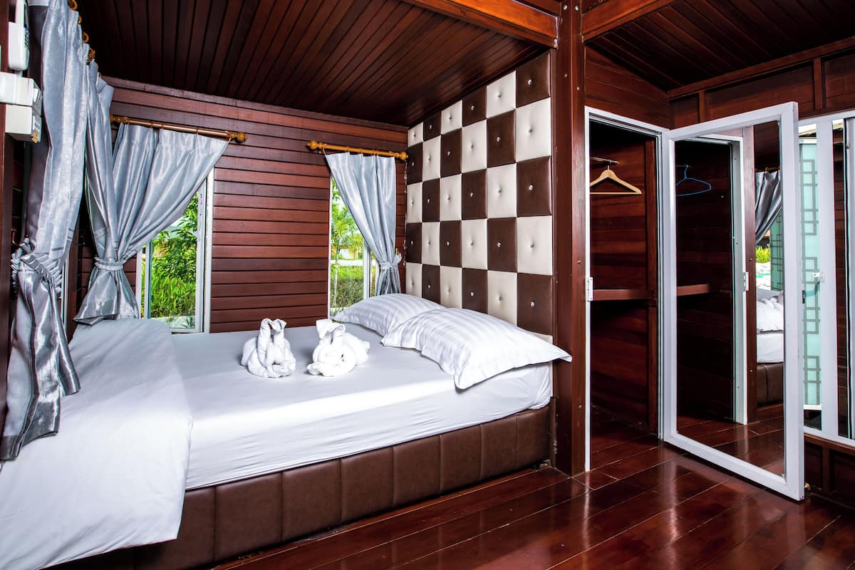 A bedroom with a large bed, a wardrobe, and a sliding door to a balcony.