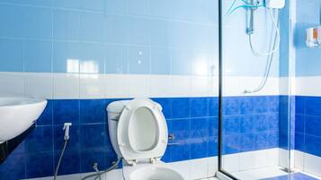 A bathroom with a white toilet, a sink, and a shower enclosure.