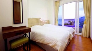 Een slaapkamer met een bed, een bureau en uitzicht op het groen.