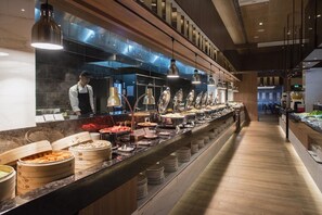 Ein Buffetbereich mit verschiedenen Speiseausgaben und einem Koch, der Speisen zubereitet.