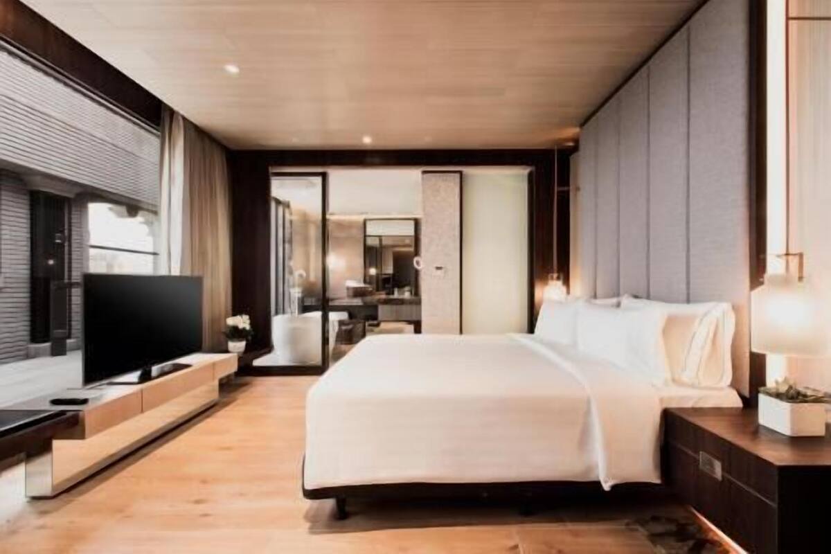 Ein modernes Hotelzimmer mit einem großen Bett, einem Flachbildfernseher und einer Schiebetür zu einem Badezimmer.