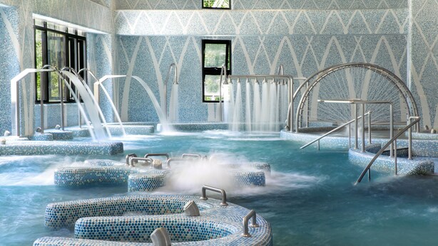 Een bubbelbadgedeelte met meerdere zitplekken en een centraal waterkunstwerk.
