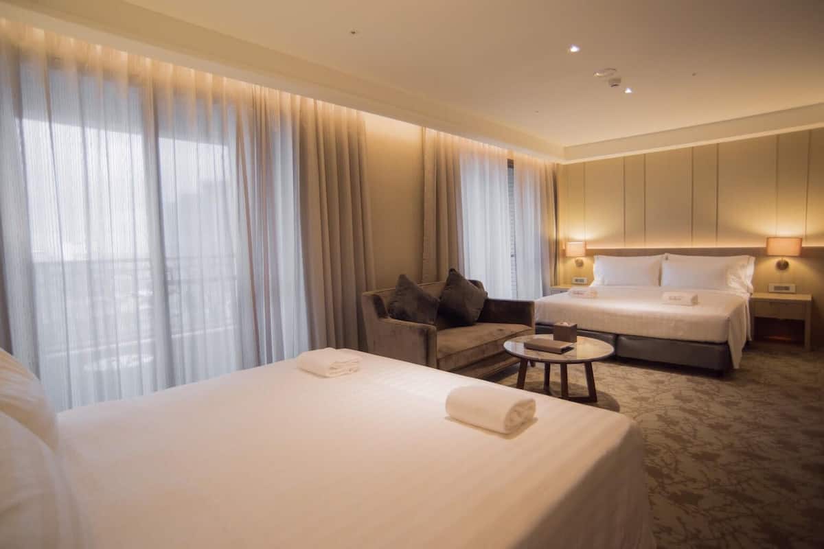 Ein Hotelzimmer mit zwei Betten, einer Couch, einem kleinen Tisch und einem Nachttisch.