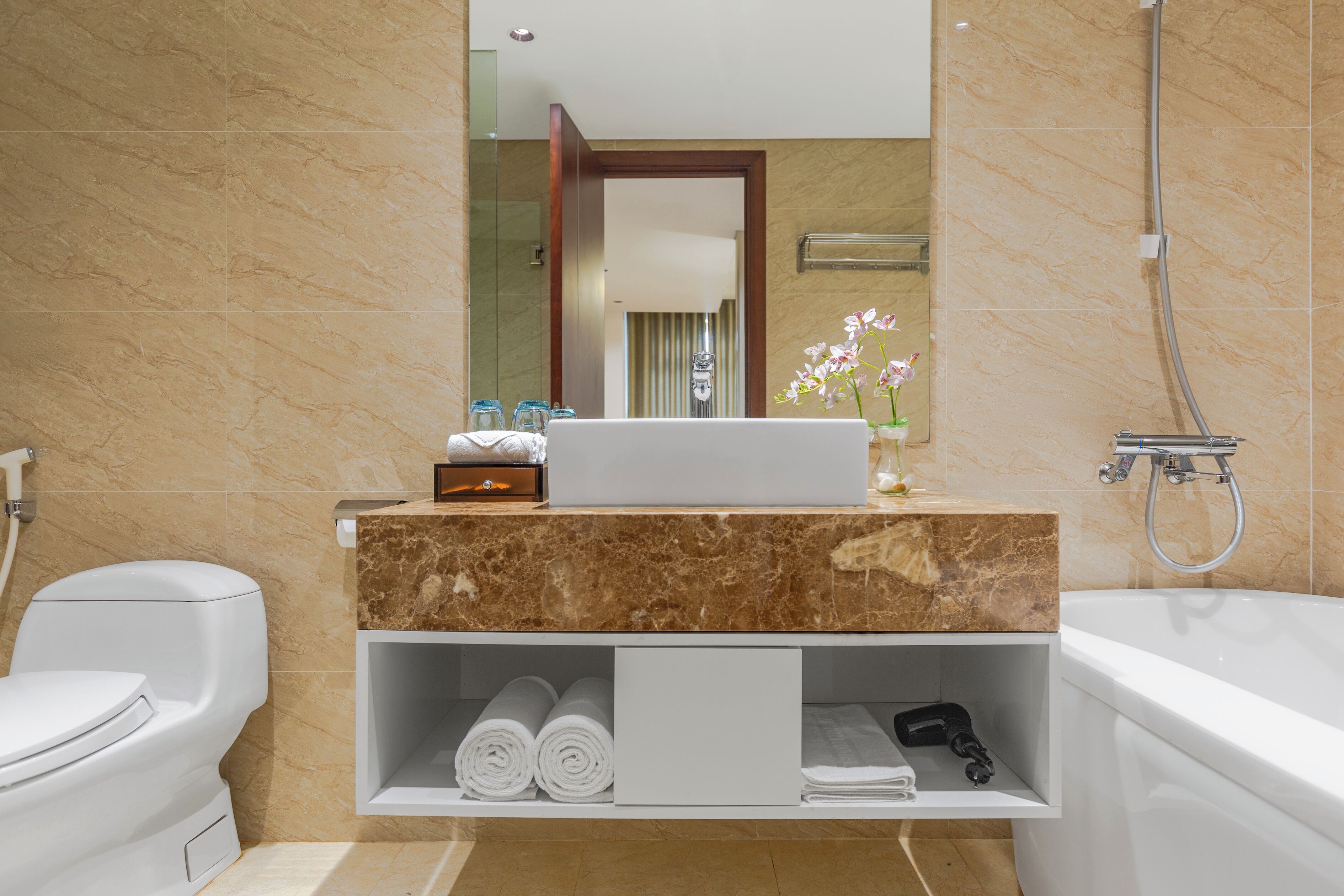A modern bathroom with a marble vanity, a white toilet, a bathtub, and a shower.