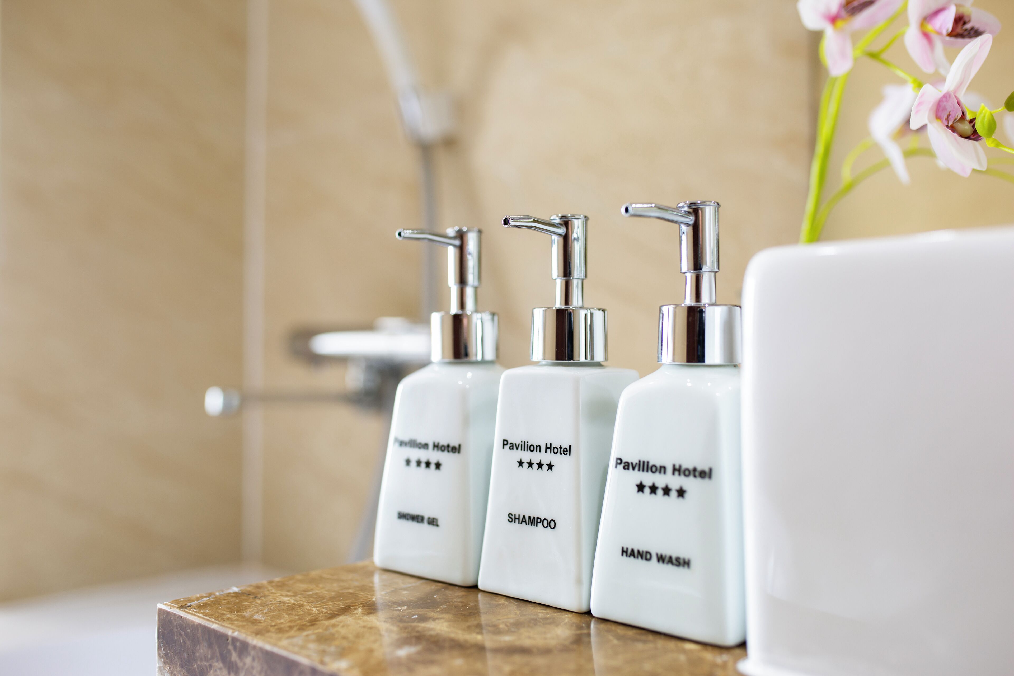 Three white hotel toiletries on a marble countertop.
