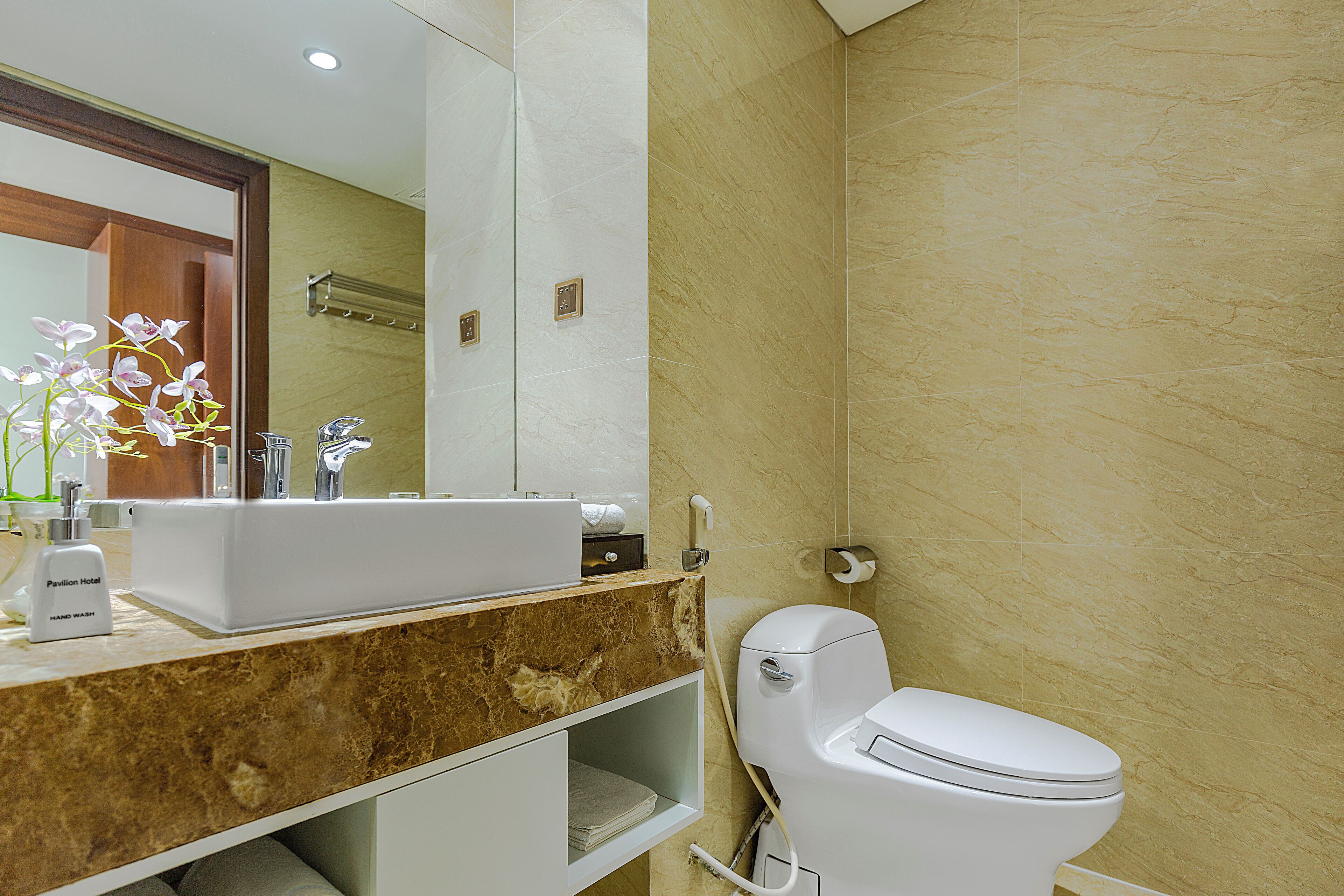 Un baño con lavamanos de mármol, inodoro y espejo.